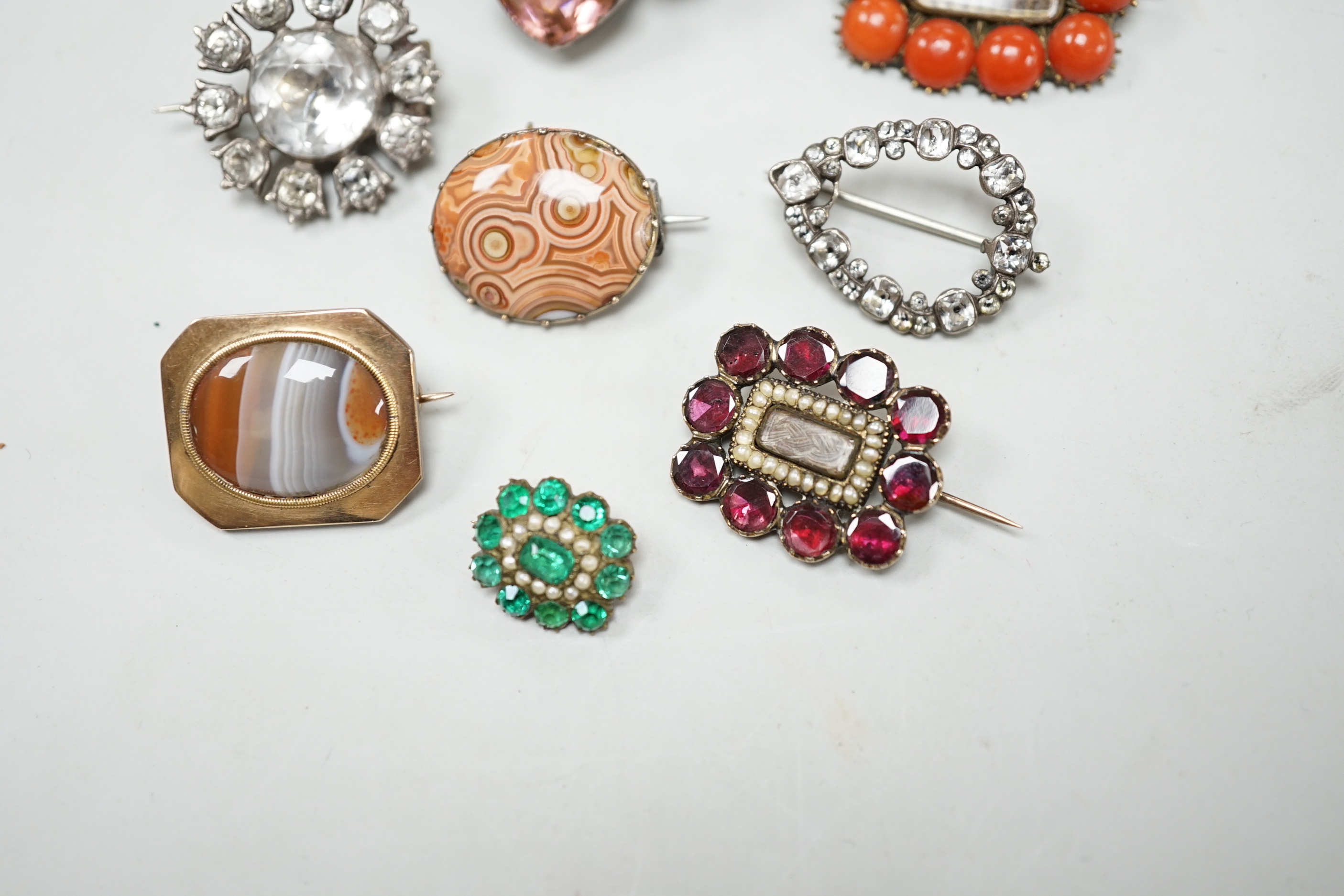 Eight assorted mainly 19th century items of jewellery, including four paste set brooches, garnet, seed pearl and plaited hair mourning brooch, a similar coral and plaited hair brooch and two chalcedony set brooches.